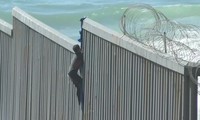Người di cư ở Mexico trèo tường biên giới để vào Mỹ