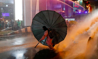 Một người biểu tình dùng ô chống lại vòi rồng của cảnh sát. (Ảnh: Reuters)