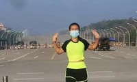 Người phụ nữ đang tập thể dục trước dàn xe quân sự