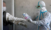 Một nhân viên y tế khử trùng găng tay cho đồng nghiệp trong một cơ sở y tế dã chiến ở phía nam Tokyo ngày 23/4/2020. (Ảnh: Reuters)