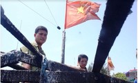 Thuyền trưởng Bùi Văn Phải và ngư dân Phạm Quang Thạnh bên con tàu cháy. Ảnh: LÊ VĂN CHƯƠNG 