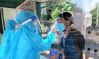 Tình nguyện viên hỗ trợ đo thân nhiệt cho người dân tại Trung tâm Y tế huyện Cư Jút