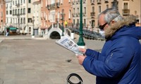 Một người dân đọc báo ở Venice (Ý) ngày 15/3. Ảnh: Reuters