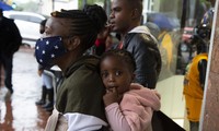 Một phụ nữ đeo khẩu trang địu con đi trên phố ở Pretoria (Nam Phi) ngày 27/11. Ảnh: AP