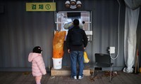 Một bé gái chờ bố lấy mẫu xét nghiệm ở Seoul (Hàn Quốc). Ảnh: Reuters