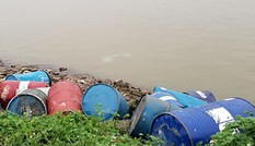 Hàng chục thùng phuy lạ rò rỉ chất đen xì mùi nồng nặc đổ xuống sông Hồng
