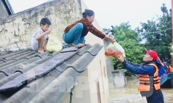 Bà Biên Thị An nhoài người nhận hàng cứu trợ