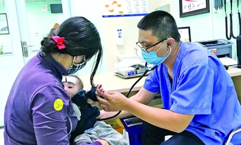 Bác sĩ Hùng khám cho bệnh nhi. Ảnh: Thái Hà