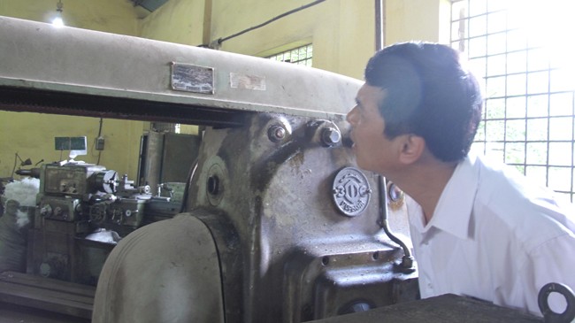 Sinh viên ngành cơ khí nông nghiệp bí đầu ra Trưởng khoa Cơ điện, Học viện Nông nghiệp Việt Nam Lê Minh Lư (SN 1961) bên một cỗ máy có tuổi đời ngang bằng với số tuổi của ông. Ảnh: HB
