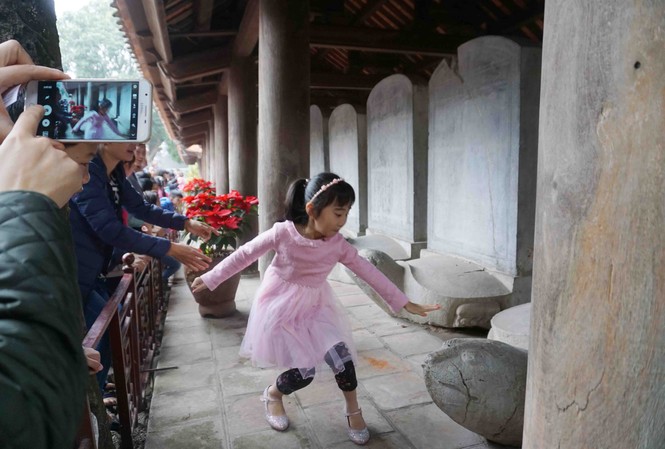 Văn Miếu đông nghẹt, người dân vô tư sờ đầu rùa Cha mẹ khuyến khích con cái vượt rào sờ đầu rùa lấy may, mặc bảo vệ nhắc nhở tới nơi tới chốn. Ảnh: Nguyên Khánh