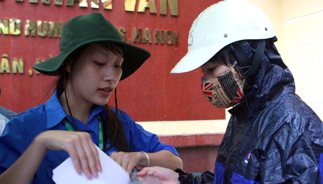 Tiếp sức mùa thi dưới mưa Tình nguyện viên tư vấn giấy tờ cho thí sinh đến đăng ký dự thi tại điểm Trường ĐH KHXH&NV. Ảnh: Xuân Tùng