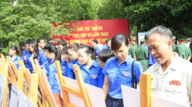 Triển lãm ảnh kỷ niệm 50 năm phong trào “Ba sẵn sàng“ Đoàn viên, thanh niên lắng nghe chia sẻ của cựu chiến binh thời kỳ Ba sẵn sàng. Ảnh: Trường Phong