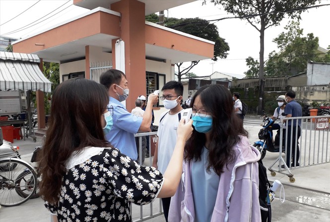 Dịch COVID-19 ở TPHCM: Không phức tạp vì biết được nguồn lây Giáo viên trường THPT chuyên Nguyễn Hữu Huân (quận Thủ Đức, TPHCM) đo thân nhiệt cho học sinh khi dịch COVID-19 tái xuất hiện trong cộng đồng. Ảnh: Huy Thịnh