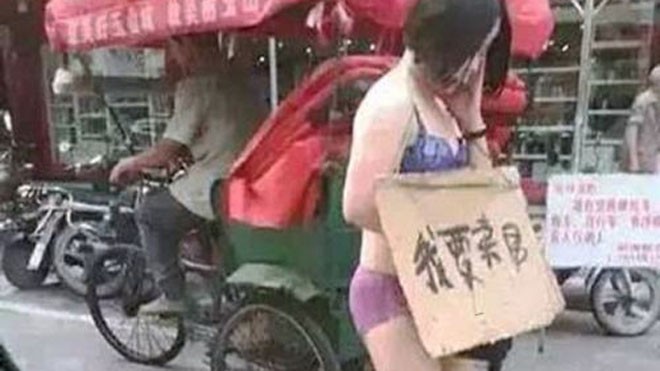 Chồng bắt vợ mặc đồ lót, đeo biển 'bán thân' diễu phố Cô Wang Ni với tấm biển "tôi bán cơ thể mình" trên cổ (Ảnh: Mirror)