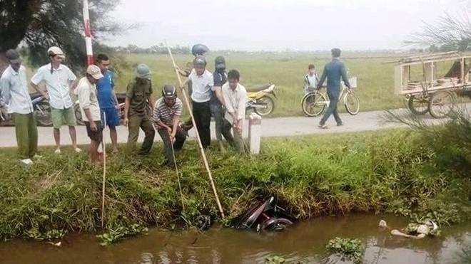 Thi thể nam thanh niên nằm dưới ao cùng xe máy Người dân trục vớt thi thể và xe máy của nạn nhân lên bờ. Ảnh. Đ.H