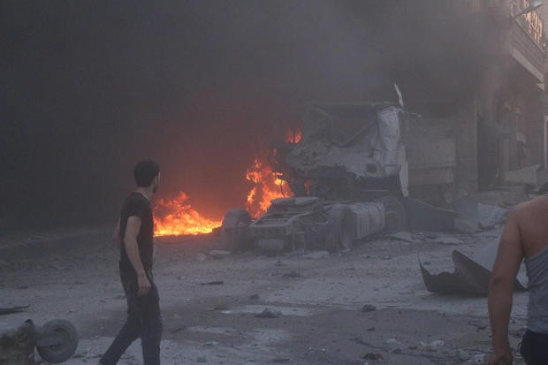 Mỹ không kích Syria, Nga lên tiếng chỉ trích Người dân Syria đứng cạnh lửa, đống đổ nát và một xe tải hư hỏng sau một vụ không kích chết người ở tỉnh Idlib hôm 28/8.