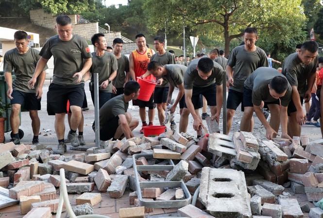 Binh sĩ Trung Quốc mặc quần shorts, áo phông xanh dọn dẹp đường phố Hong Kong Binh sĩ Trung Quốc giúp dọn gạch đá trên đường phố Hong Kong. Ảnh: SCMP.