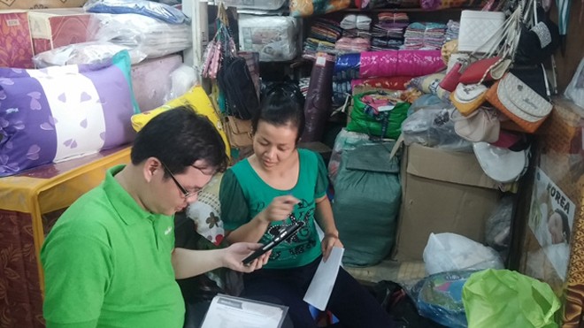 MuaBanNhanh.com và nền tảng M-Commerce cho mọi người Hình ảnh nhân viên MuaBanNhanh.com hướng dẫn các tiểu thương tại chợ bán hàng bằng smartphone