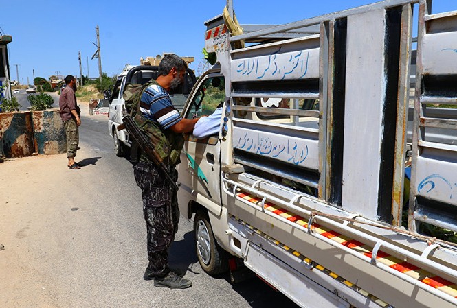 Xung đột ở Idlib – câu chuyện không của riêng Syria Các tay súng của liên minh các nhóm nổi dậy Jaish al Fateh kiểm tra xe tải tại tỉnh Idlib hôm 18/7. Ảnh: Reuters