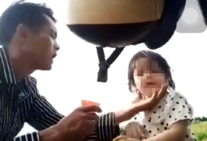 Bản tin 8H: Điều tra vụ cha cho con gái 3 tuổi uống ‘nước lạ’ T. ép con gái 3 tuổi uống nước từ chai thuốc màu xanh. (Ảnh: Cắt từ clip)