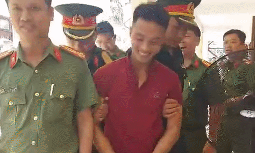 Triệu Quân Sự cười khi bị còng tay, dẫn giải về trại tạm giam