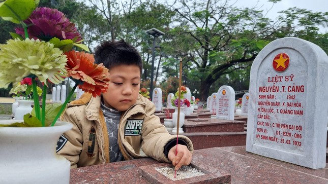 Một em nhỏ được ba mẹ chở tới, đi thắp hương cho từng phần mộ trong nghĩa trang.