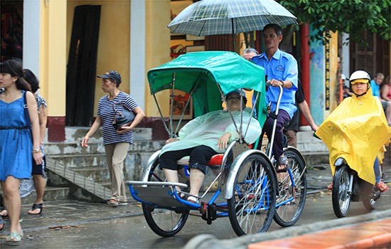 Mặc áo mưa ngồi xích lô dạo phố.