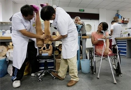 Hongyan vui vẻ ngồi nhìn các bác sĩ chỉnh sửa đôi chân giả của mình
