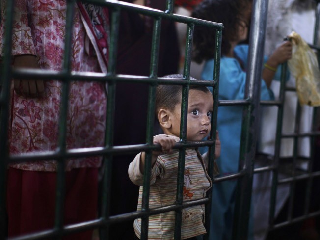Một em bé Pakistan đứng bên cạnh chị gái đợi đến lượt nhận gạo từ thiện ở Beri Imam, Islamabad