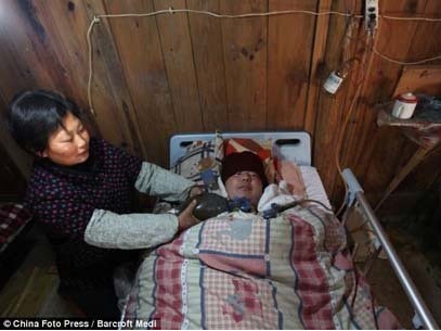 Bà Wang Lanqin ngồi cạnh con trai, tay liên tục bóp chiếc cầu khí bơm oxy vào phổi con
