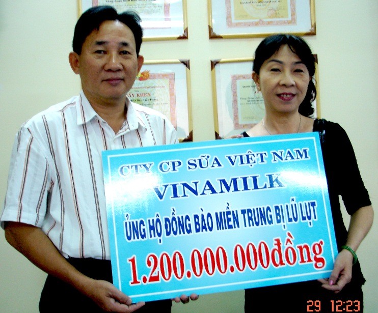 Đại diện Vinamilk trao tấm biển ghi số tiền mặt cứu trợ đồng bào miền Trung cho đại diện báo Tiền Phong