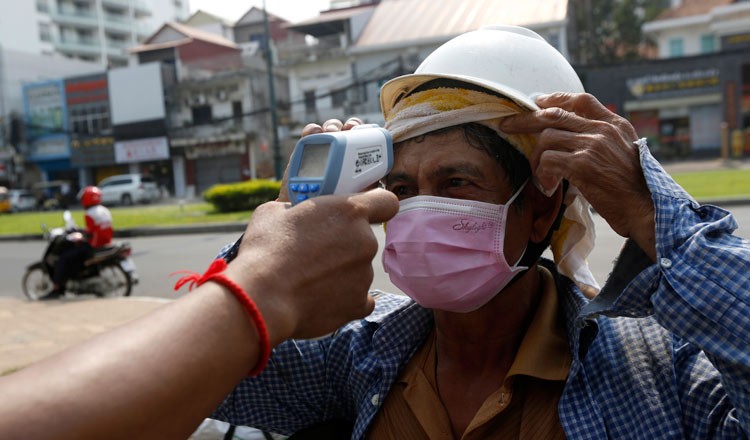 Một người đàn ông được đo nhiệt độ bên ngoài khách sạn ở Phnom Penh. (Ảnh: Khmer Times)