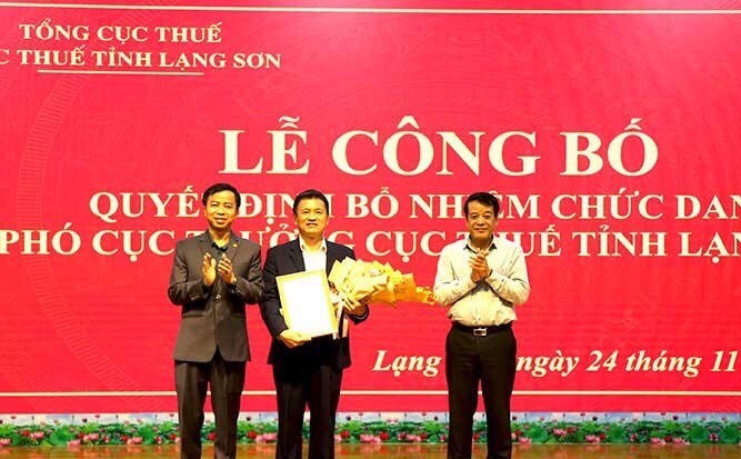 Ông Bùi Minh Bằng (giữa) nhận quyết đinh và hoa chúc mừng của lãnh đạo ngành thuế .Ảnh: T. Dũng 