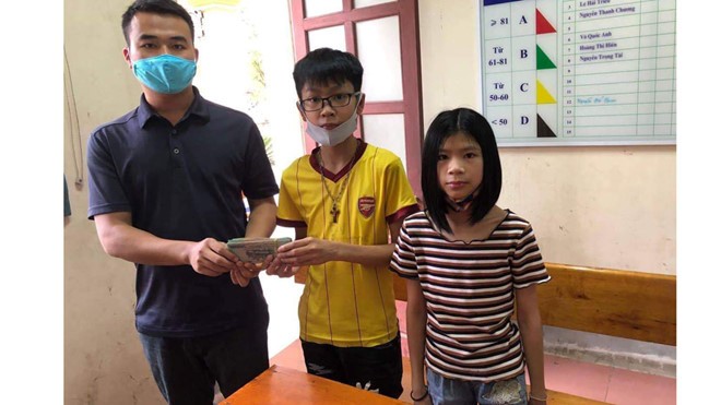 Em Hải (áo vàng ở giữa) trao lại số tiền nhặt được cho đại diện Công an phường Nam Hà.