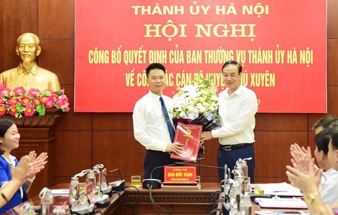 Phó Bí thư Thành ủy Đào Đức Toàn trao quyết định và hoa chúc mừng ông Nguyễn Xuân Thanh.