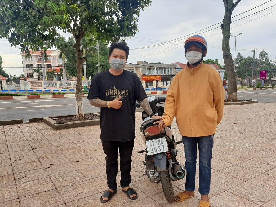 Anh Lai (bìa trái) trao tặng chiếc xe máy cho anh Hồng để về Bình Định sáng 6/8