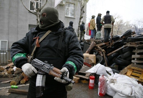 Một tay súng đứng cạnh hàng rào chắn, bên ngoài trụ sở cảnh sát ở Sloviansk. Ảnh: Reuters