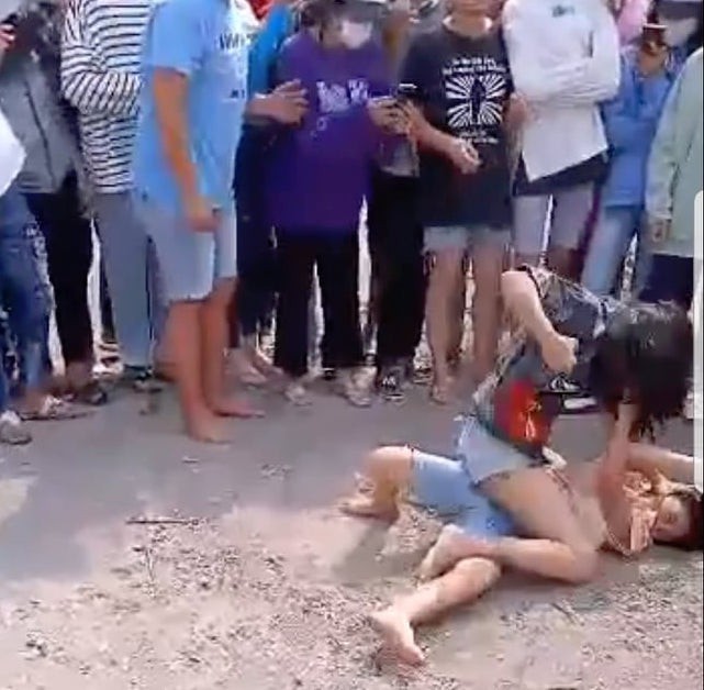 Nhiều người đứng bên ngoài cổ vũ 2 nữ sinh đánh nhau.