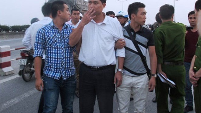 Bác sĩ Nguyễn Mạnh Tường (áo trắng) bị dẫn giải ra cầu Thanh Trì thực nghiệm hiện trường