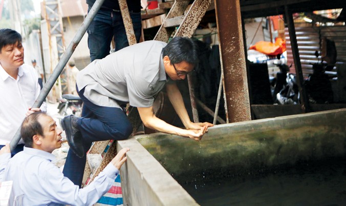 Phó Thủ tướng Vũ Đức Đam đích thân vục nước kiểm tra bọ gậy, loăng quăng trong bể nước tại một công trường xây dựng ở phường Láng Thượng, thuộc quận Đống Đa, Hà Nội, chiều 28/7. Ảnh: Như Ý. 