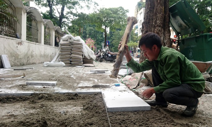 Công nhân đang lát đá vỉa hè trên phố Nguyễn Du - Hà Nội chiều 21/1. Ảnh: Như Ý.