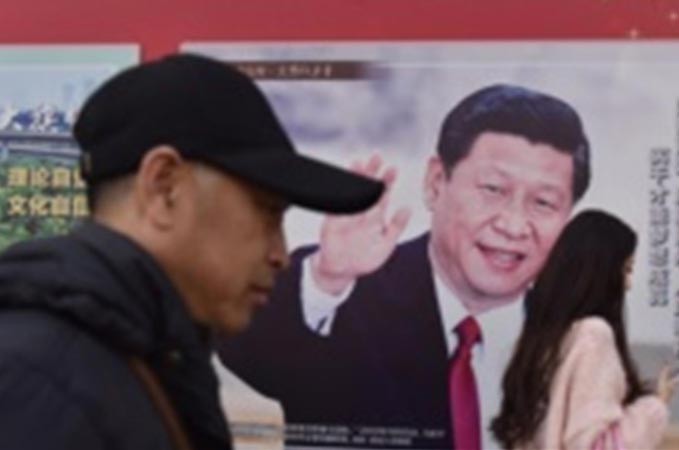 Người dân đi qua tấm poster hình Tổng bí thư, Chủ tịch Trung Quốc Tập Cận Bình trên một tuyến phố ở Bắc Kinh ngày 26/2. Ảnh: Getty Images.