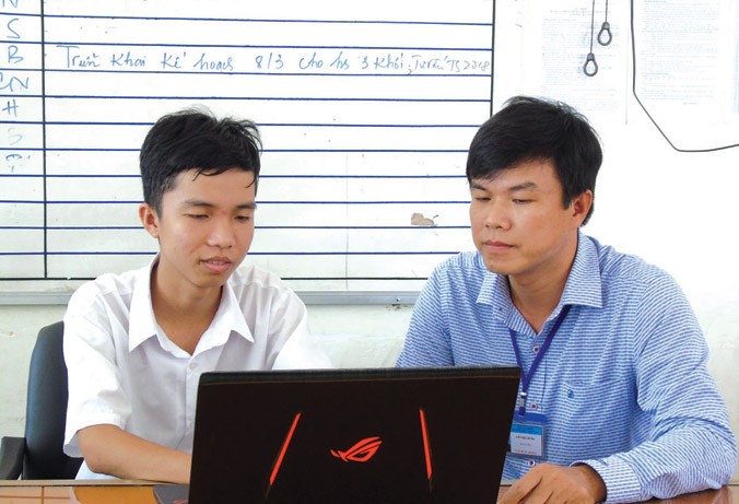 Em Trần Lê Duy (bên trái) và thầy Võ Việt Dũng kiểm tra một số phần mềm đã lập trình. Ảnh: Kim Hà.