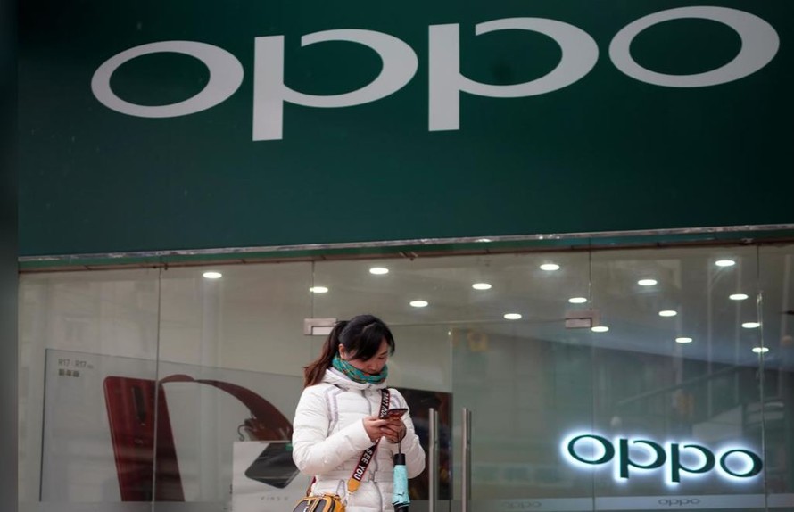 Một phụ nữ đứng trước một cửa hàng của hãng điện thoại Oppo. Ảnh: Reuters 