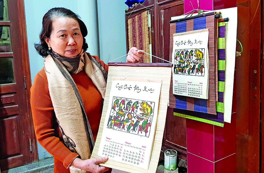 Nghệ nhân Nguyễn Thị Oanh giới thiệu cuốn lịch năm Canh Tý, với bức tranh “Đám cưới chuột” Ảnh: KIẾN NGHĨA 
