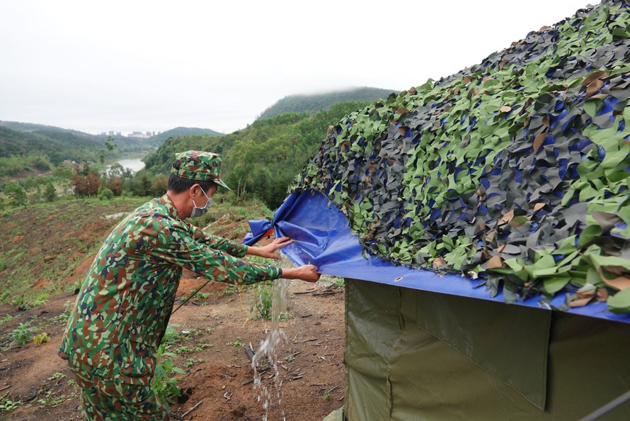 Trung tá quân nhân chuyên nghiệp Bùi Văn Bách tháo nước đọng trên mái che lán dã chiến Ảnh: Nguyễn Minh