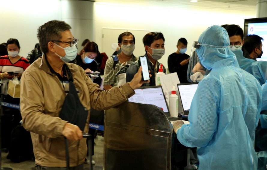 Nhân viên kiểm dịch kiểm tra khai báo y tế, hộ chiếu người nhập cảnh tại sân bay Tân Sơn Nhất - ảnh: Ngô Bình, mạnh thắng