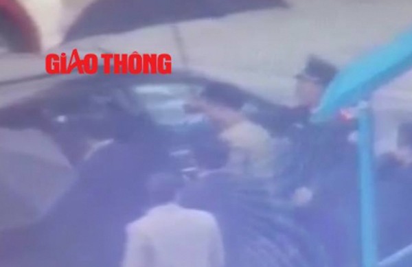 Lực lượng an ninh dẫn giải Vũ “nhôm” ra xe ô tô (ảnh cắt từ clip Báo Giao thông)