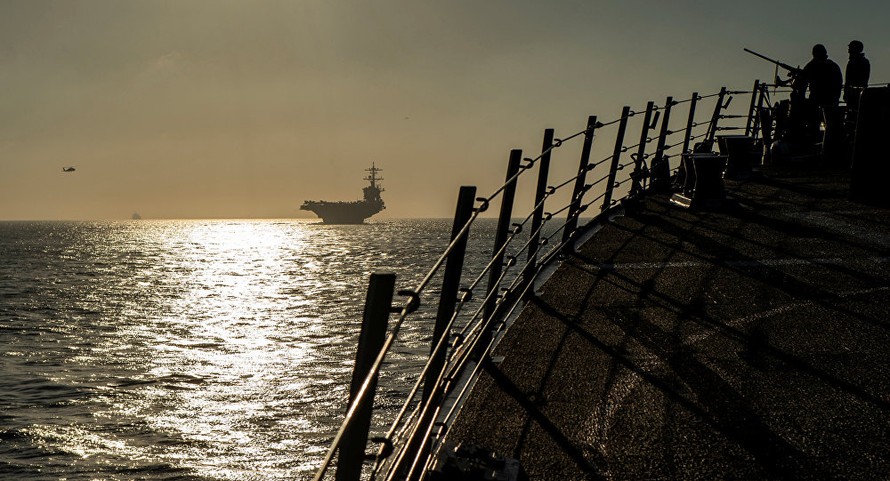 Quân nhân Mỹ trên tàu khu trục USS Bainbridge, phía xa là tàu sân bay USS Abraham Lincoln trên eo biển Gibralta ngày 13/4 ảnh: Reuters/Sputnik