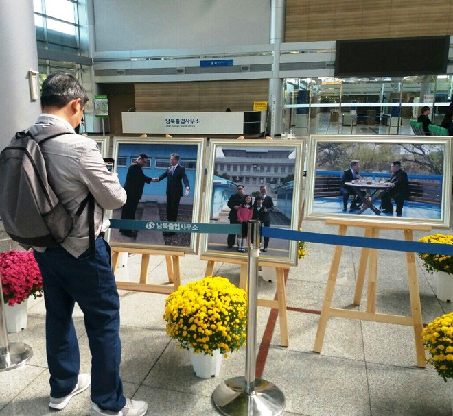 Khách du lịch trước những tấm ảnh lãnh đạo hai miền Triều Tiên gặp nhau hồi tháng 9 vừa qua (X.T)